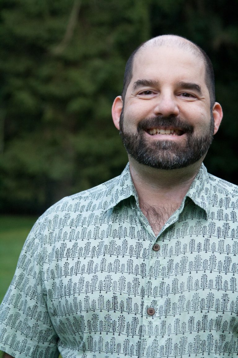 Brian Mount, RMT, smiling outdoors in front of green trees